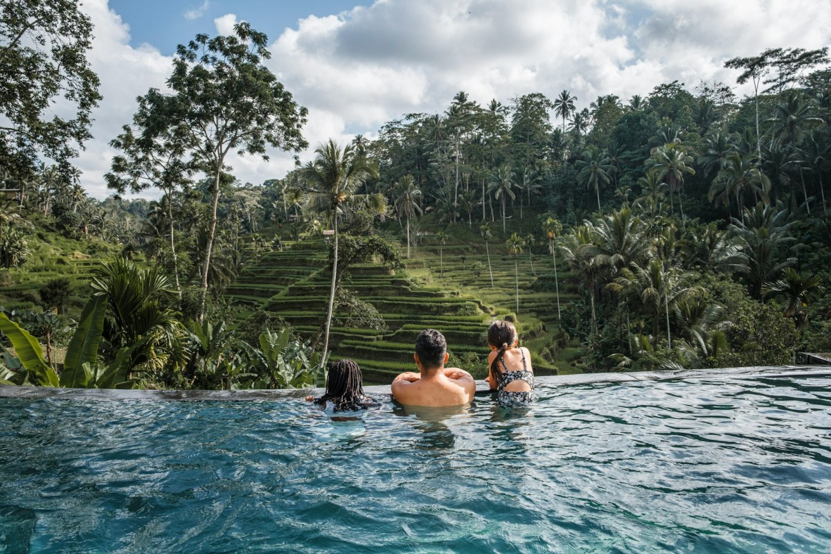 Family at infinity pool overlooking Bali rice terraces lush green landscape