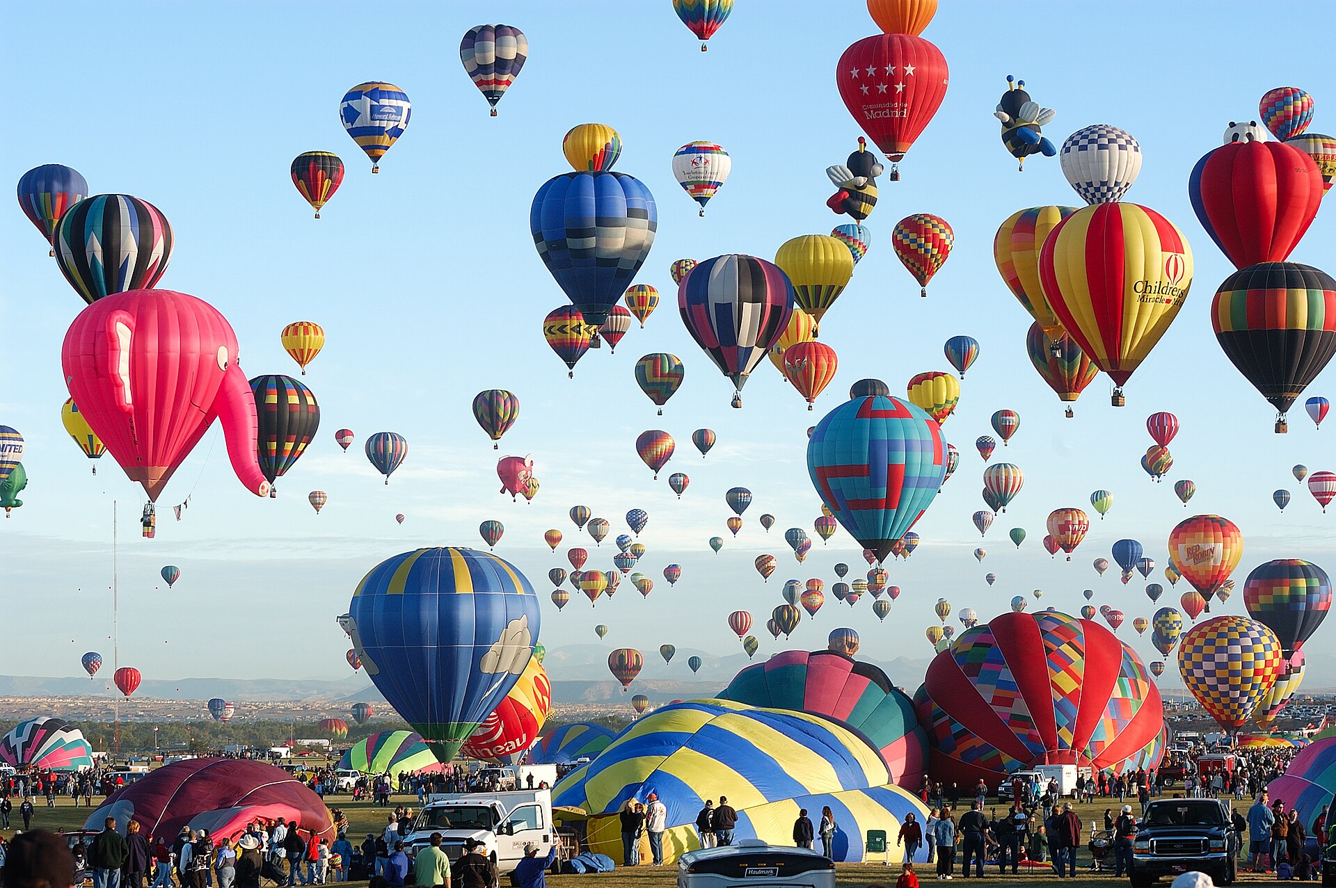 Hundreds of colorful hot air balloons filling a blue sky above the Albuquerque Balloon Fiesta launch field